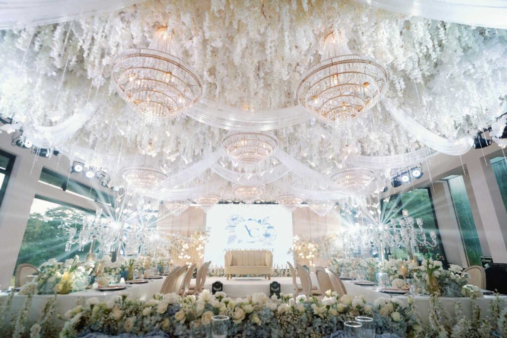 A beautifully decorated wedding reception featuring white flowers and elegant chandeliers, captured by Jay Mayuga Photography.